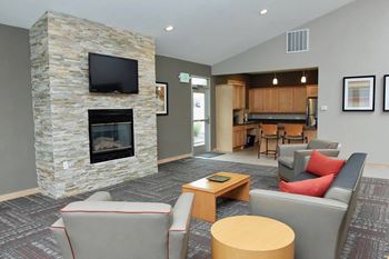 A living room with a stone fireplace and grey couches.